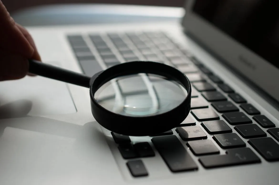 Lupa sobre un teclado: verificación de información del candidato